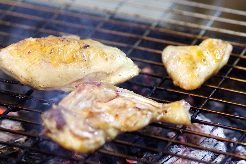 若鶏の炭火焼きを炭火で焼いている写真